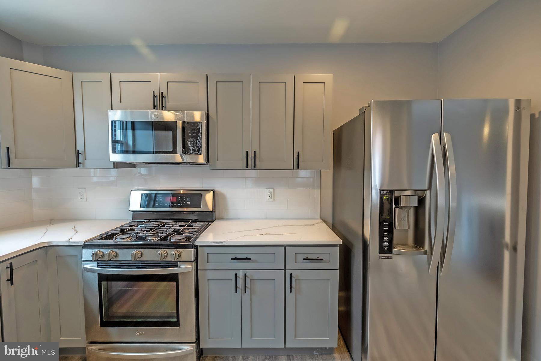 3104 Stirling Street Philadelphia, PA 19149 - Photo 9 of 27 a kitchen with stainless steel appliances granite countertop a stove a refrigerator and a microwave