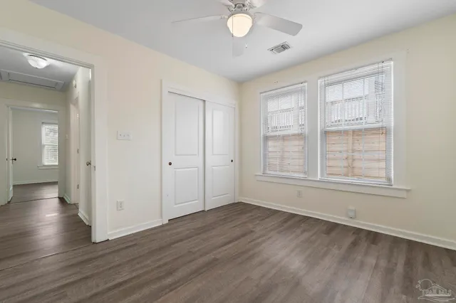 an empty room with wooden floor and windows
