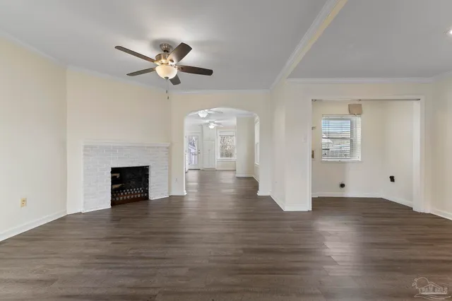 an empty room with wooden floor chandelier fan and windows