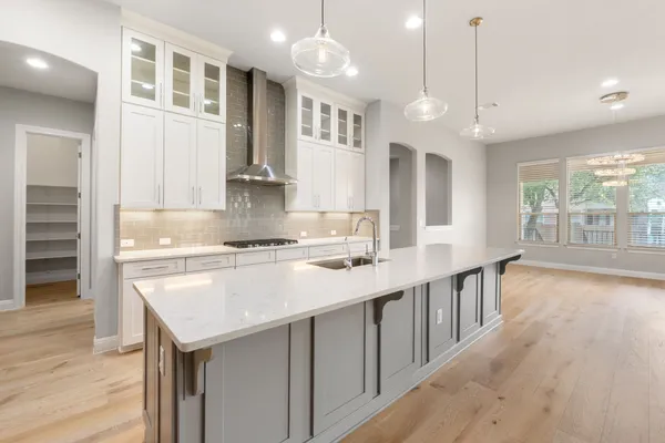 a kitchen with stainless steel appliances granite countertop a sink a stove and a wooden floors