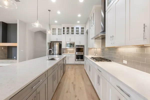 a large kitchen with stainless steel appliances lots of counter space wooden floor and a sink