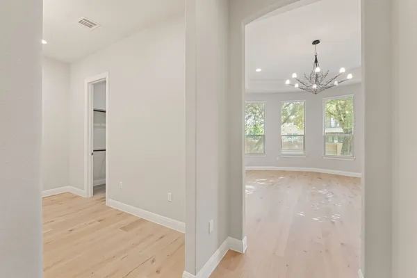 a view of a hallway with wooden floor and chandelier