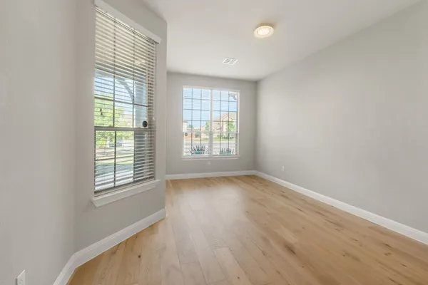 an empty room with wooden floor and windows