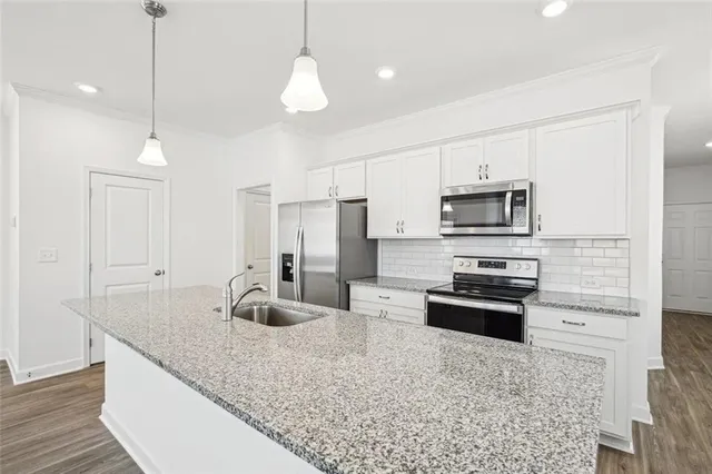 a kitchen with stainless steel appliances granite countertop a refrigerator a stove a kitchen island a dining table and chairs with wooden floor