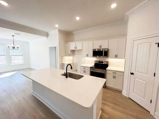 a kitchen with a refrigerator a stove top oven a sink and dishwasher with wooden floor