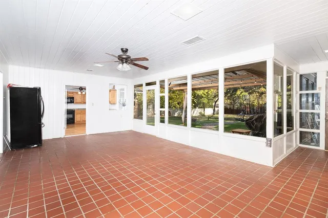 a view of an empty room with a window and a kitchen