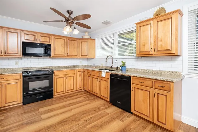 a kitchen with granite countertop a sink cabinets stainless steel appliances and a window