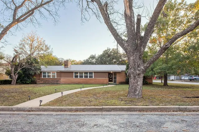 a front view of a house with a yard and trees