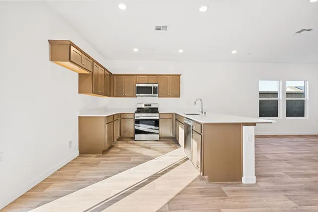 a kitchen with stainless steel appliances granite countertop a stove a sink and a microwave