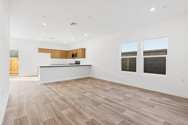 a view of an empty room with a window and wooden floor