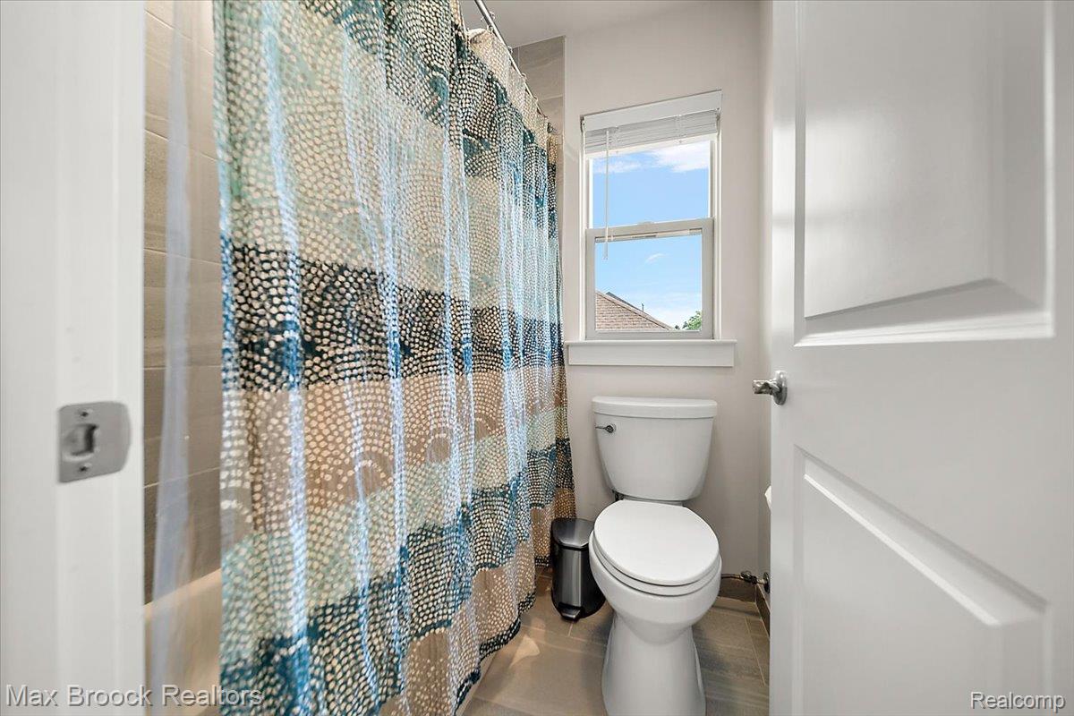 1942 Nottingham Drive Rochester, MI 48307 - Photo 59 of 97 Bathroom featuring a window, white toilet, and tub with tiled surround