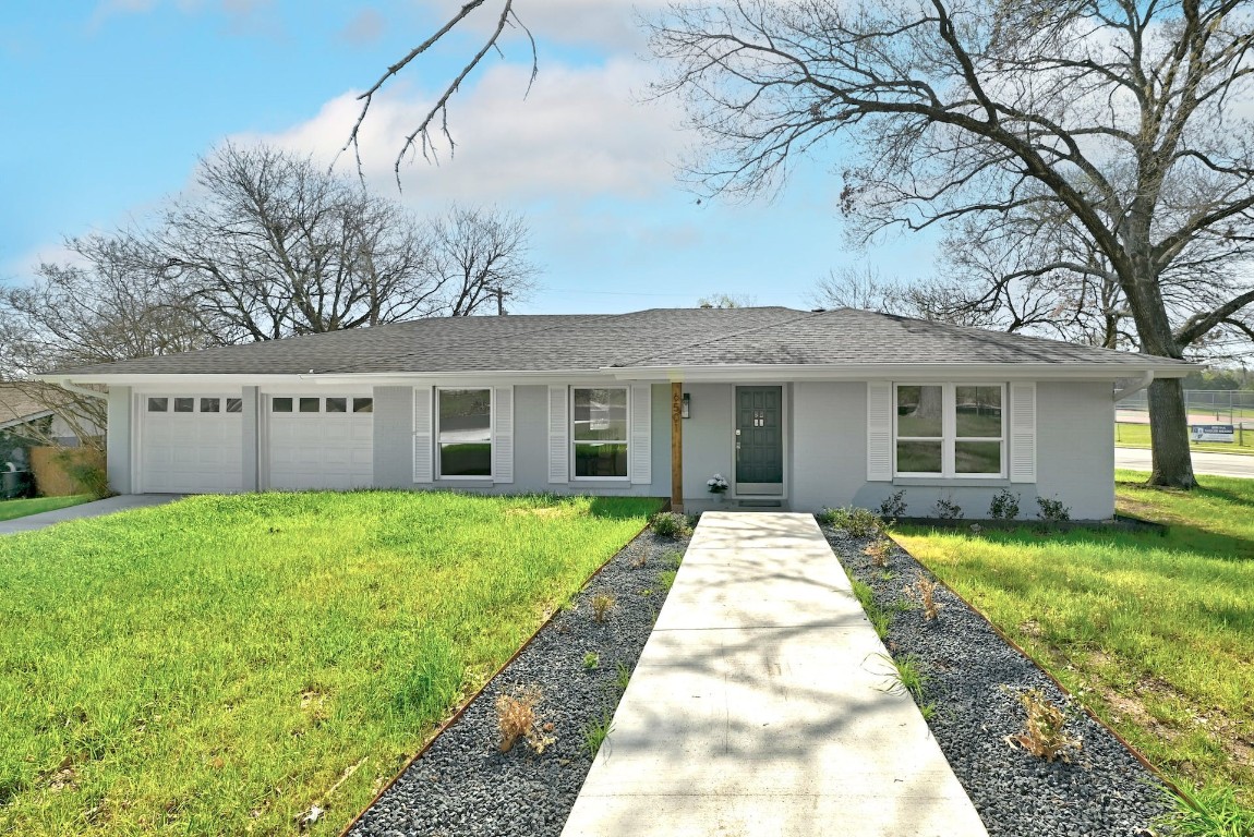 a view of a brick house with a big yard and large trees