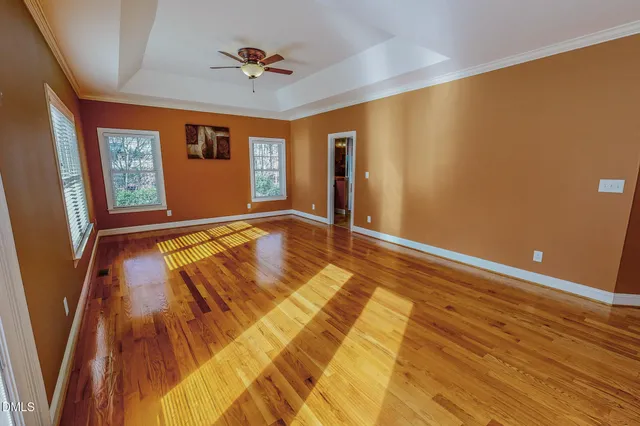 a view of empty room with wooden floor and fan