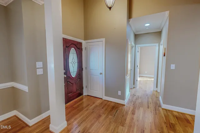 a view of an empty room with wooden floor and a ceiling fan