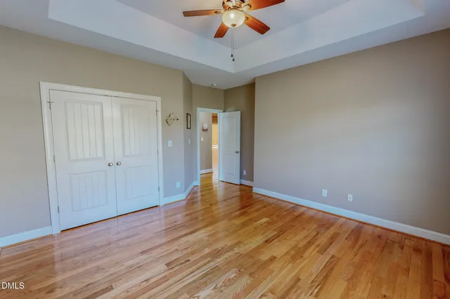 a view of empty room with wooden floor and fan