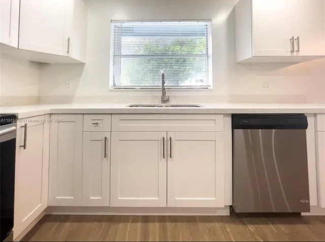 a view of kitchen with granite countertop white cabinets and window