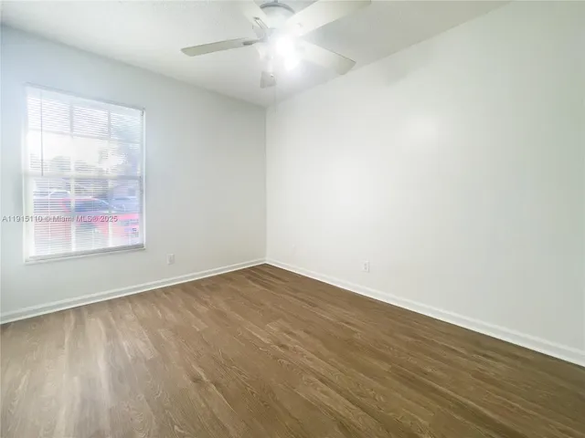 an empty room with wooden floor and window