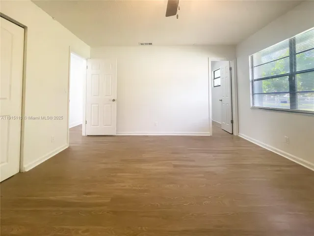 an empty room with wooden floor closet and ceiling fan