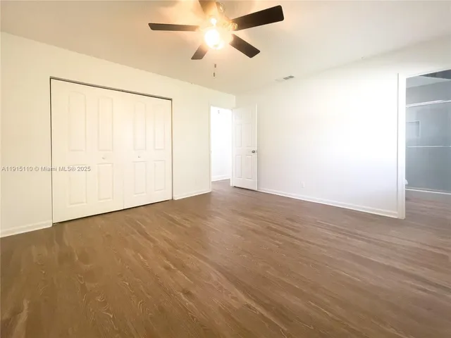 an empty room with wooden floor closet and windows