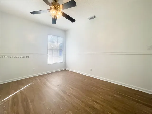 an empty room with wooden floor closet and windows