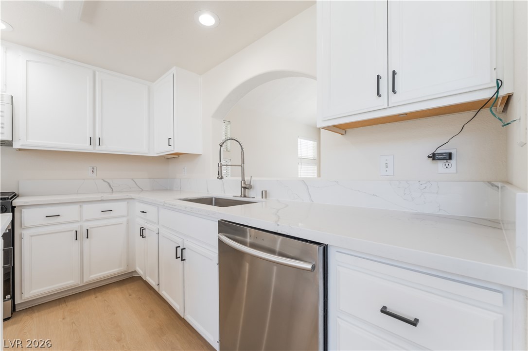 8872 Chapman Point Las Vegas, NV 89129 - Photo 8 of 29 A pristine white kitchen features a large stainless steel sink and appliances, ideal for any culinary endeavor.