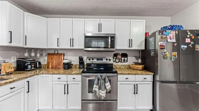 a kitchen with stainless steel appliances granite countertop a refrigerator stove and white cabinets