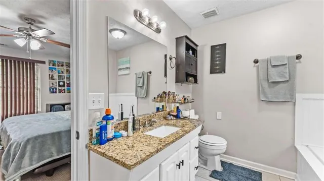 a bathroom with a granite countertop sink a toilet and a mirror