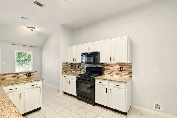 a kitchen with white cabinets and appliances