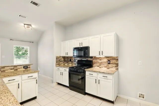 a kitchen with white cabinets and appliances