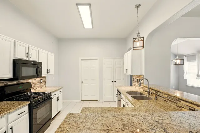 a kitchen with granite countertop a stove a sink and a refrigerator