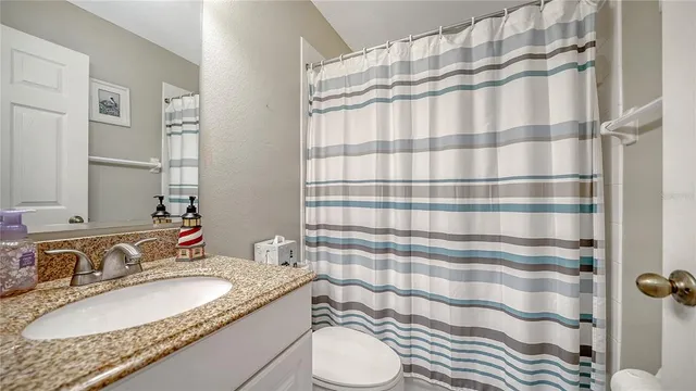 a bathroom with a granite countertop sink a toilet and shower curtain