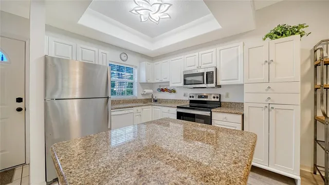 a kitchen with granite countertop stainless steel appliances a refrigerator a stove a microwave and cabinets