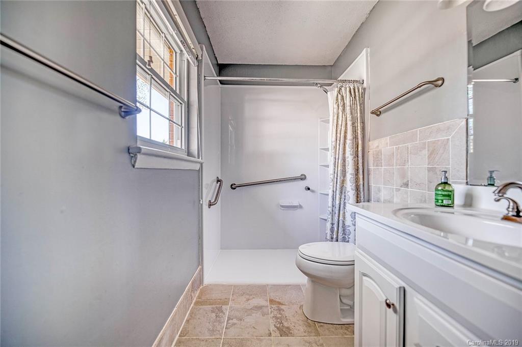 12001 Idlewild Road, Unit 7 Matthews, NC 28105 - Photo 19 of 29 a bathroom with a granite countertop sink toilet and shower