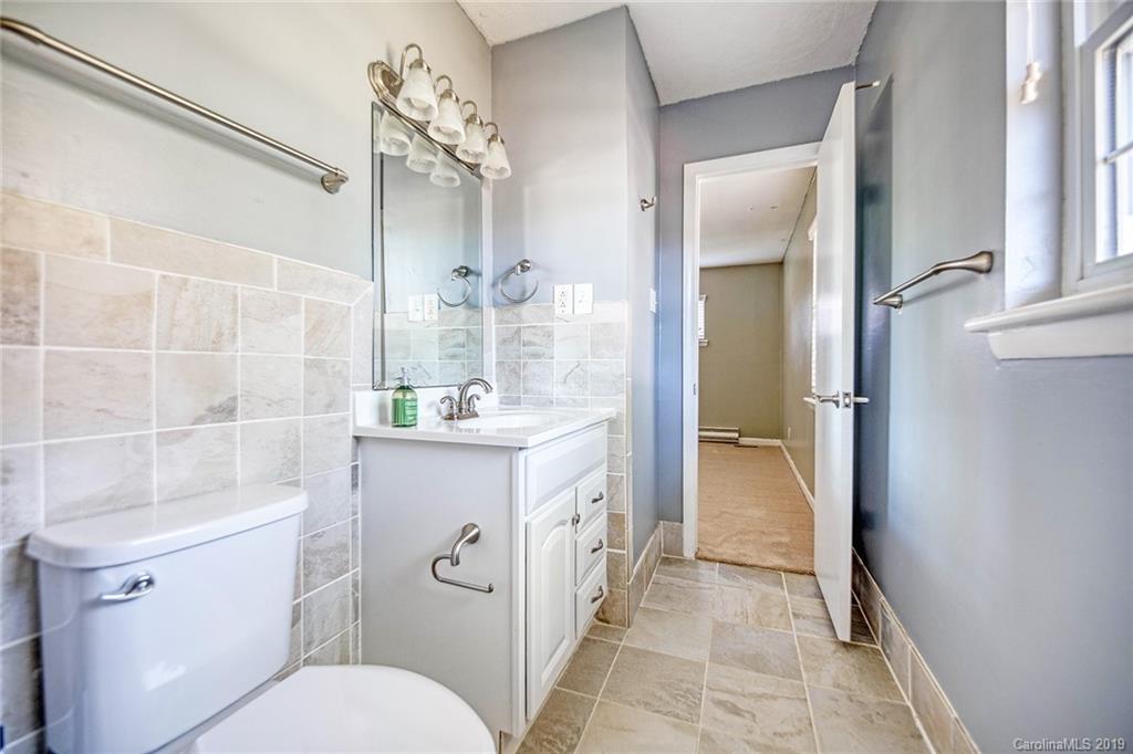 12001 Idlewild Road, Unit 7 Matthews, NC 28105 - Photo 20 of 29 a spacious bathroom with a sink a toilet a mirror and shower
