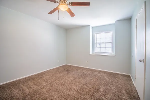 an empty room with windows and fan