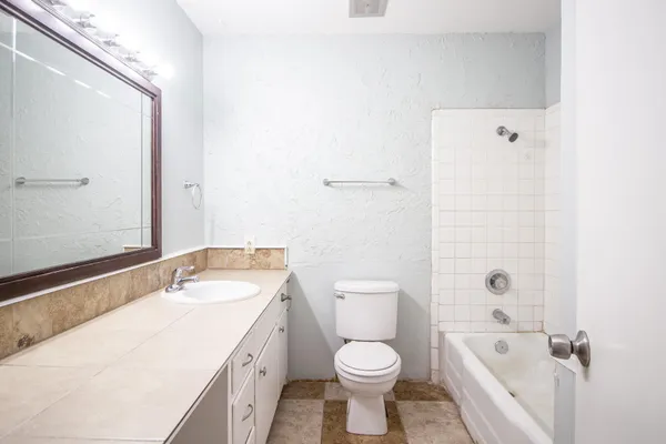 a bathroom with a granite countertop sink a toilet and bathtub