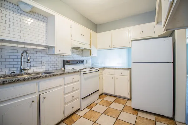a kitchen with white cabinets sink and a refrigerator