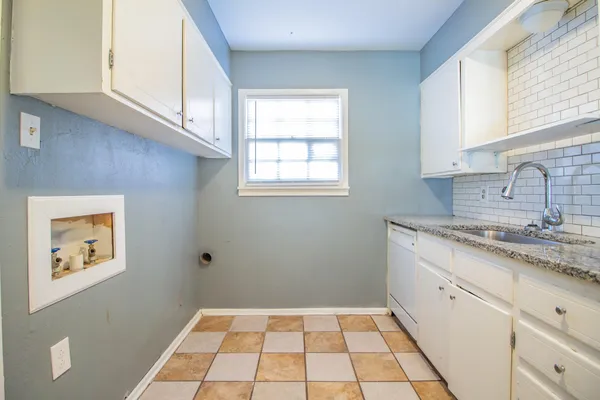 a kitchen with a sink a stove cabinets and a window