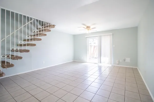 a view of an empty room with stairs and a chandelier