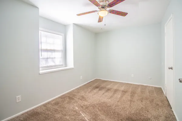 an empty room with a window and a fan