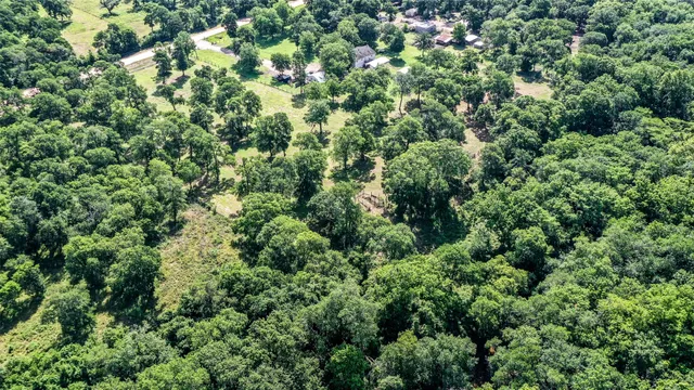 an aerial view of residential house with outdoor space and trees all around