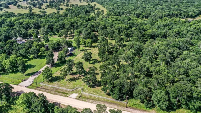 an aerial view of residential house with outdoor space and trees all around