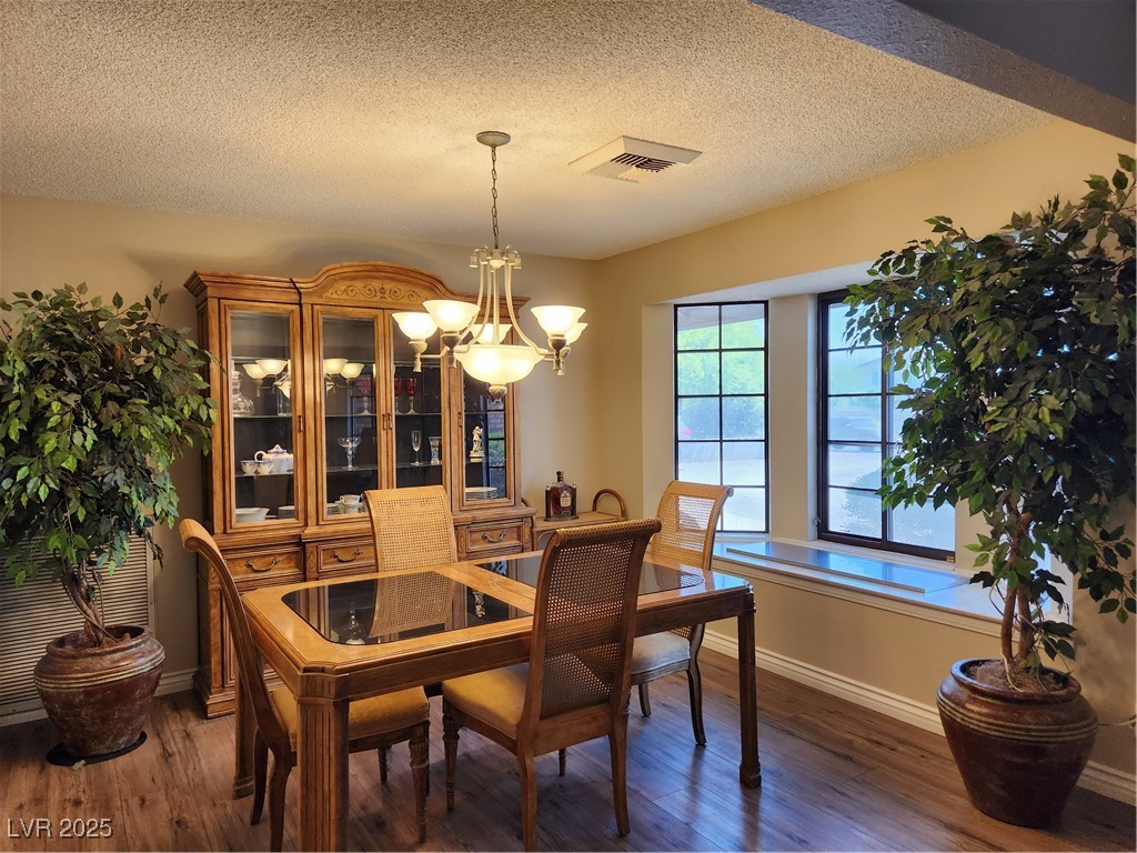 2645 South Lindell Road Las Vegas, NV 89146 - Photo 6 of 30 Dining area featuring a chandelier, wood finished floors, and a textured ceiling