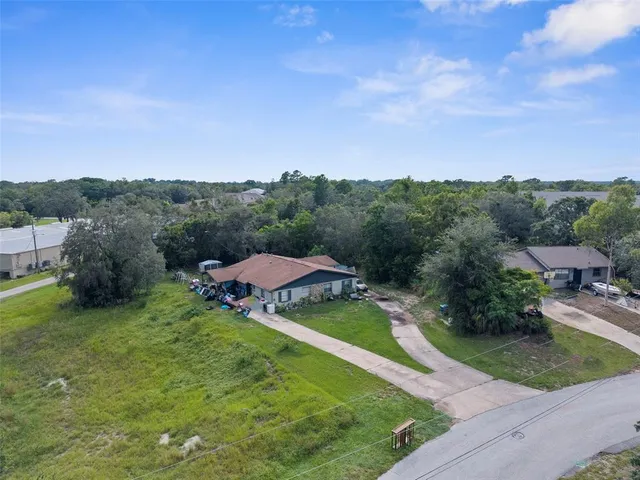 an aerial view of residential houses with outdoor space and trees