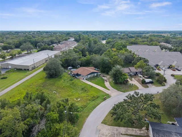 an aerial view of a houses with outdoor space and trees all around