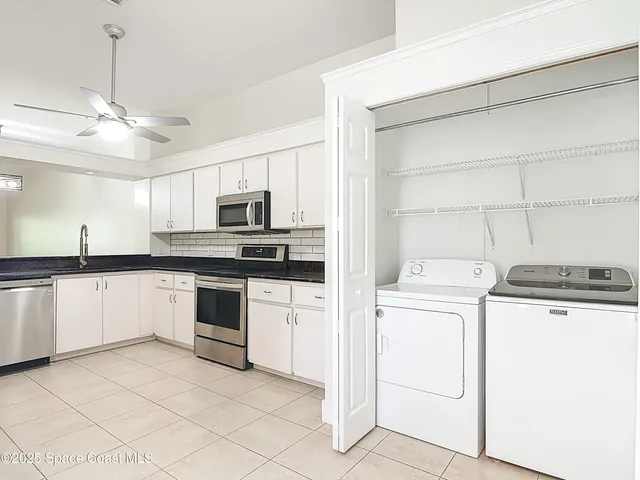 an empty room with windows and chandelier fan