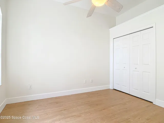 an empty room with wooden floor chandelier and windows
