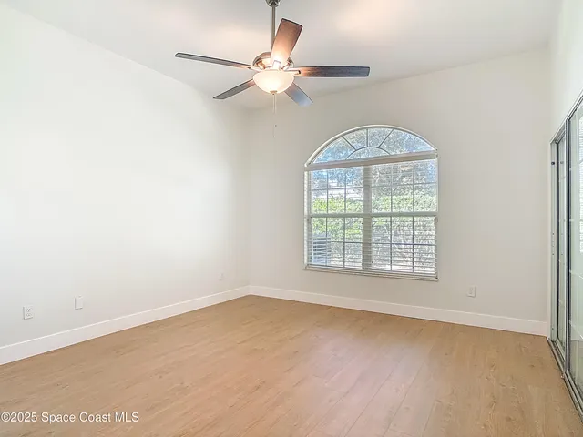 an empty room with wooden floor closet and windows