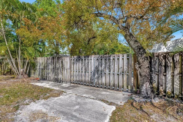 a backyard of a house with large trees and wooden fence