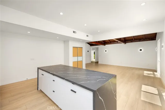 a view of an empty room with wooden floor and a ceiling fan